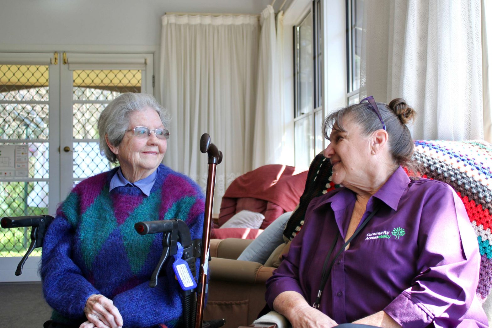 Aged person and support worker talking in lounge room